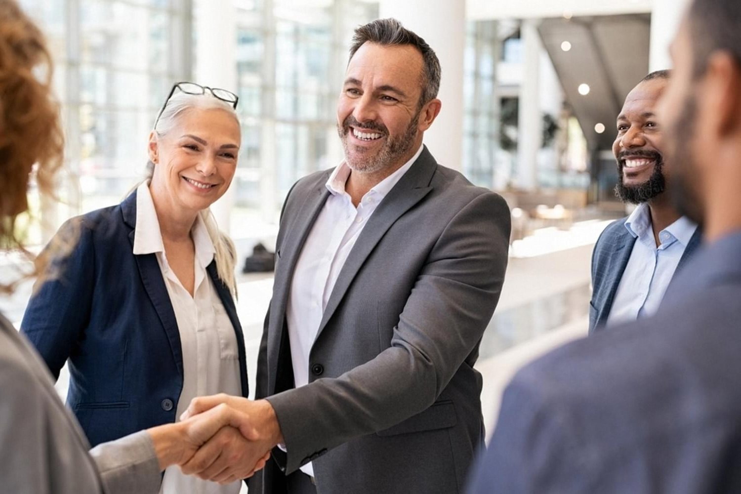 Business executives shaking hands in a modern office lobby after closing a due diligence meeting